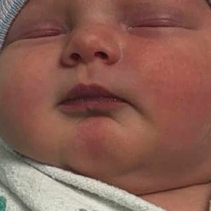 Bellann is registered to the contest to win money with this photo: baby, blanket, clothing, crying, face, hat, head, newborn, person, sad, skin, sleeping