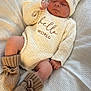 baby, sleeping, knit_hat, knit_booties, knit_sweater, blanket, infant, cozy, cute, soft_texture, pom_pom, resting, newborn, warm_clothing, indoors, child, peaceful, small_hands, small_feet, portrait