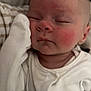 baby, sleeping, face, rosy_cheeks, onesie, mitten, blanket, infant, closeup, peaceful, soft, young_child, resting, couch, comfortable, skin, head, expressionless, person, indoors