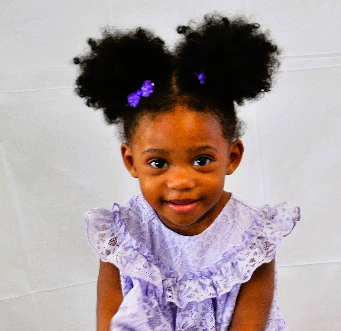 Leneah is registered to the contest to win money with this photo: afro, baby_toddler_clothing, black_hair, chin, eyebrow, face, fashion, fashion_design, happy, headgear, human, joy, magenta, people, person, purple, skin, sleeve, smile, toddler