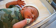 Santonio joined the competition — help win amazing prizes! newborn, baby, infant, sleeping, hospital, bassinet, camouflage_clothing, onesie, white_cap, wristband, hand, face, peaceful, closeup, skin, person, child, indoors, healthcare, portrait