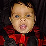 baby, child, face, blue_eyes, smiling, red_clothing, black_clothing, checkered_pattern, car_seat, seatbelt, portrait, close_up, infant, young_child, happy, cute, indoors, dark_background, buttoned_shirt, person
