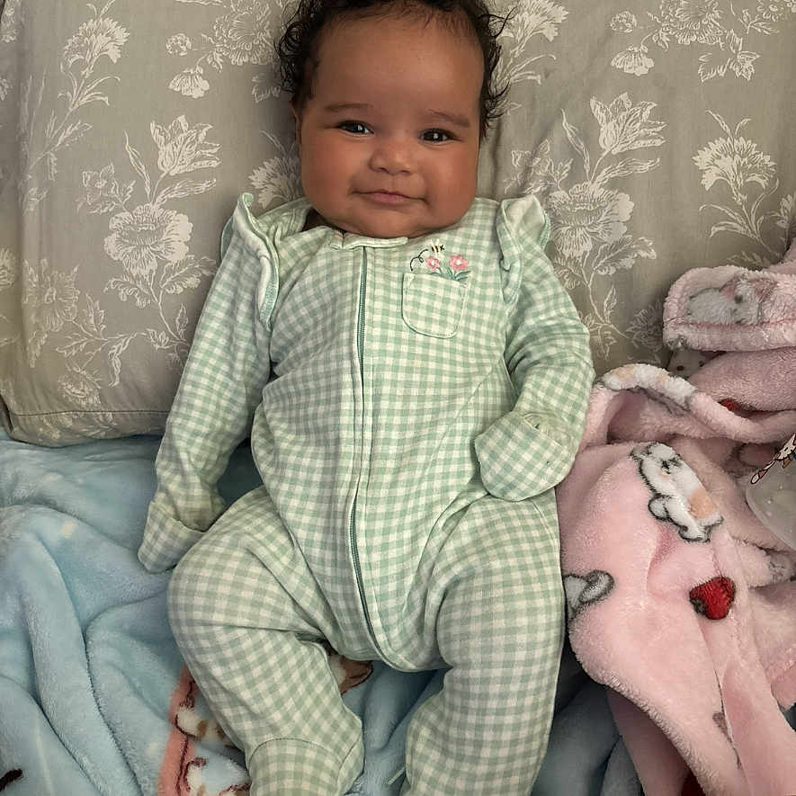 Lailani Jackson is registered to the contest to win money with this photo: baby, blanket, blue_blanket, child, cozy, cute, face, green_checkered, hair, indoors, infant, lying_down, onesie, person, pillow, pink_blanket, portrait, resting, smile, soft_toys