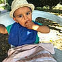 Mylan a rejoint le concours — aidez-le/la à gagner de superbes lots ! toddler, child, hat, blue_bib, green_shirt, plastic_chair, outdoor, fruit, eating, curious, expression, blanket, nature, sunlight, grass, trees, person, portrait, daylight, seat