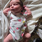 Charli is registered to the contest to win money with this photo: baby, newborn, sleeping, onesie, strawberry_pattern, blanket, soft_light, peaceful, infant, cute, child, resting, bed, fabric, skin, hand, leg, clothing, portrait, indoor