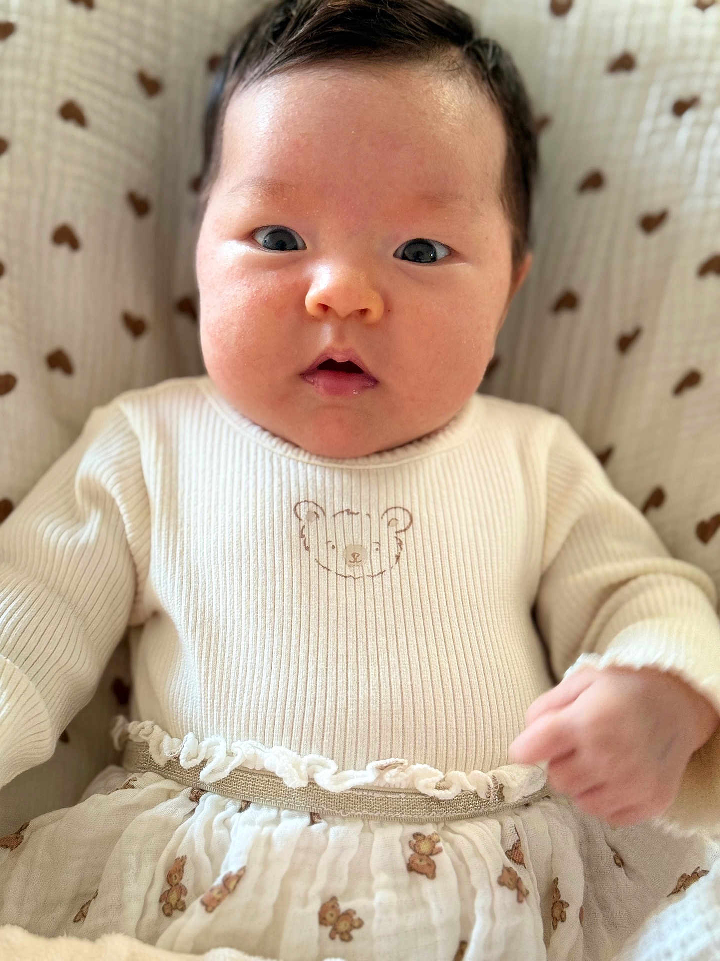 Emmy a rejoint le concours — aidez-le/la à gagner de superbes lots ! baby, infant, face, closeup, clothing, sweater, bear_illustration, skirt, blanket, pattern, heart_pattern, cute, chubby_cheeks, wide_eyes, person, child, soft_lighting, indoors, portrait, lying_down