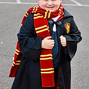 Oliver is registered to the contest to win money with this photo: black, child, clothing, costume, curly_hair, cute, fantasy, happy, magic, outdoor, pavement, person, portrait, red, scarf, smiling, standing, wizard_robe, yellow, young