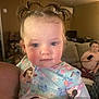 toddler, child, pigtails, pajamas, cartoon, person, indoor, living_room, sofa, remote_control, shirtless, couch, adult_arm, rosy_cheeks, young_child, home, furniture, cute, portrait, family