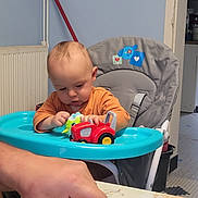 Théo a rejoint le concours — aidez-le/la à gagner de superbes lots ! baby, blue_tray, bread, child, cooking, cutting, face, family, food, furniture, hand, high_chair, home, indoor, kitchen, orange_shirt, person, playing, table, toy