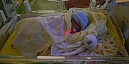 Théo participe au concours pour gagner de l'argent avec cette photo : architecture, baby, bed, blanket, bonnet, building, childbirth, clothing, cradle, crib, furniture, glove, hat, head, hospital, infantbed, newborn, person, sleeping, tape