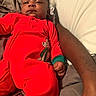 Quintavious is registered to the contest to win money with this photo: adult, arm, baby, bed, blanket, calm, child, face, family, hand, indoor, infant, looking_at_camera, lying_down, onesie, photography, pillow, portrait, red_outfit, soft_lighting