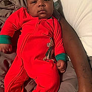 Quintavious is registered to the contest to win money with this photo: adult_arm, baby, bed, bedding, calm, child, cozy, eyes, face, indoor, infant, jumpsuit, lying_down, photography, portrait, red_outfit, short_hair, sitting, teddy_bear, 家庭