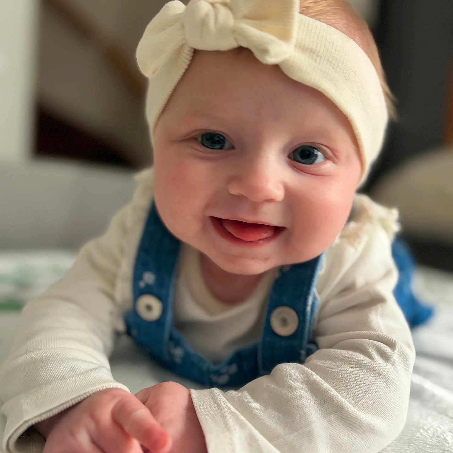 Laëlynne participe au concours pour gagner de l'argent avec cette photo : adorable, baby, big_eyes, blanket, bow, buttons, closeup, cute, denim_overalls, hands, headband, indoor, infant, portrait, rosy_cheeks, shallow_depth_of_field, smile, soft_light, tongue_out, tummy_time