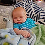 baby, sleeping, blanket, infant, cushion, blue_shirt, striped_clothing, indoor, carpet, flooring, hand, peaceful, child, comfort, home, seat, rest, nap, furniture, soft