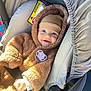 baby, child, car_seat, pacifier, brown_clothing, hat, smile, happy, infant, seatbelt, sunlight, cozy, fuzzy, cute, person, car, safety, portrait, indoor, warm