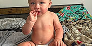 Karson joined the competition — help win amazing prizes! baby, bed, blanket, casual, child, clutter, curious, diaper, expression, finger_in_mouth, foot, furniture, hand, headboard, indoor, mohaawk, person, room, sitting, skin