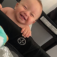Karson is registered to the contest to win money with this photo: baby, smiling, playpen, hand, blanket, indoor, happy, infant, child, tooth, face, skin, cute, grin, holding, mesh, black, white, pattern, cozy
