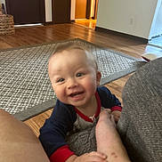 Karson joined the competition — help win amazing prizes! baby, casual, child, clothing, crawling, cute, foot, furniture, hand, happy, home, indoors, infant, living_room, person, playful, rug, smiling, wood_floor, young
