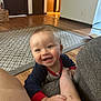 baby, casual, child, clothing, crawling, cute, foot, furniture, hand, happy, home, indoors, infant, living_room, person, playful, rug, smiling, wood_floor, young