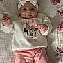 baby, bow, child, clothing, cozy, cute, floral_blanket, happy, headband, indoors, infant, lying_down, minnie_mouse, person, pink_pants, playful, portrait, smiling, sweater, tongue_out