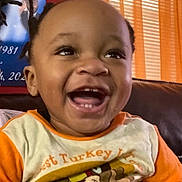 Gregory joined the competition — help win amazing prizes! toddler, child, smiling, laughing, braids, shirt, turkey, thanksgiving, orange, couch, indoor, portrait, happy, person, face, clothing, home, window, curtains, celebration