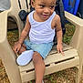 Gregory is registered to the contest to win money with this photo: toddler, child, smiling, sitting, white_shoes, denim_shorts, white_tank_top, plastic_chair, outdoor, grass, curly_hair, happy, person, casual_clothing, playful, young_child, footwear, summer_clothing, nature, daylight