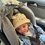 Naïm participe au concours pour gagner de l'argent avec cette photo : baby, car_interior, car_seat, child, clothing, cute, denim_jacket, expression, face, hat, headwear, infant, person, safety_harness, seat, seatbelt, smile, soft_toys, window, young_child