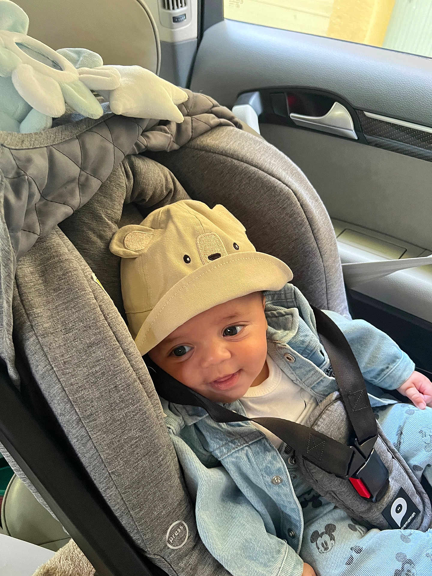 Naïm participe au concours pour gagner de l'argent avec cette photo : baby, car_seat, hat, denim_jacket, smile, infant, child, seatbelt, car_interior, cute, clothing, face, person, safety_harness, window, seat, headwear, expression, young_child, soft_toys