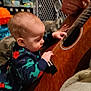 baby, child, guitar, music, hand, onesie, dinosaur_pattern, indoor, carpet, toy, adult, string_instrument, furniture, floor, curious, playing, interaction, person, closeup, home