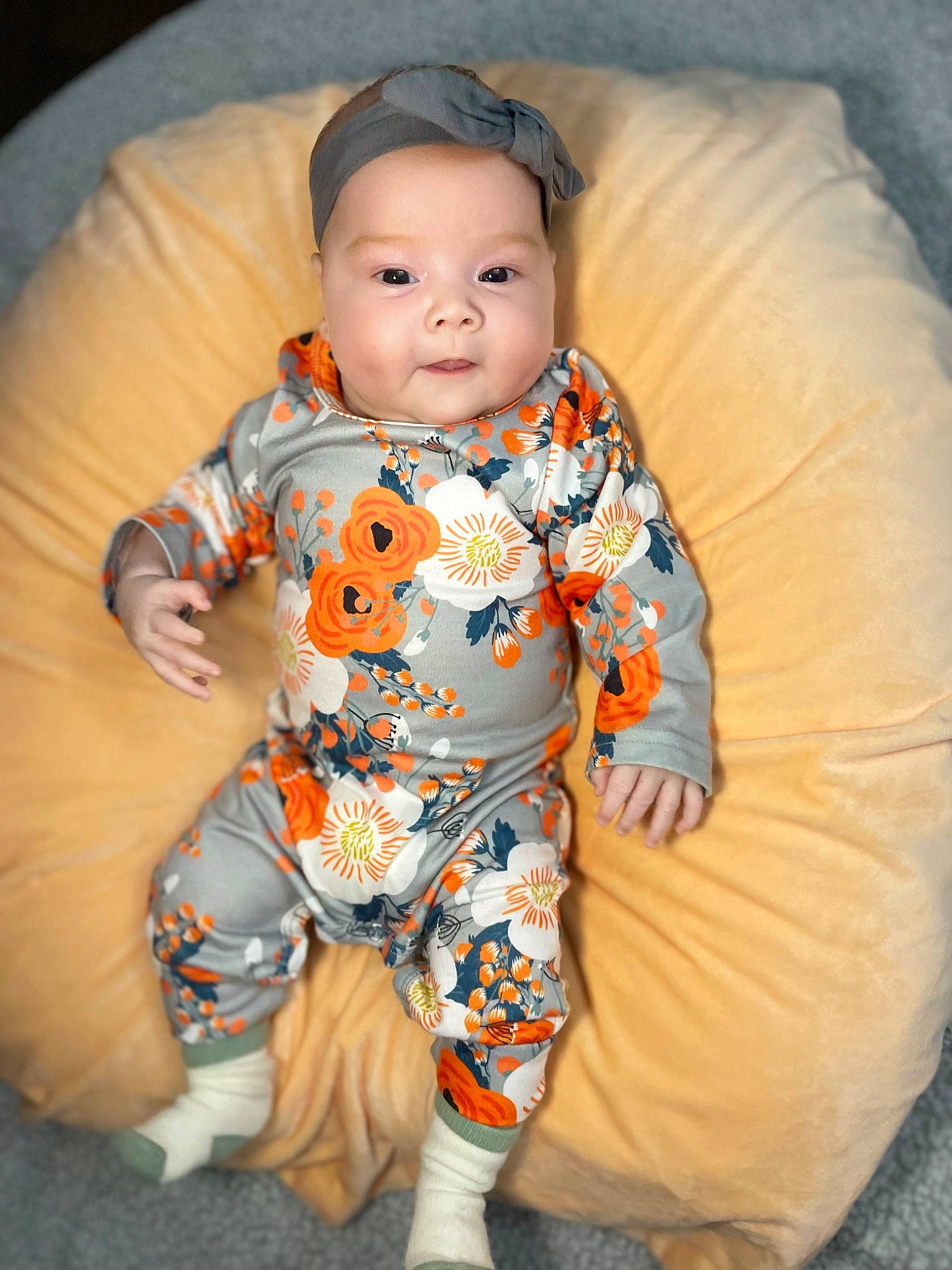 Kyah is registered to the contest to win money with this photo: baby, baby_toddler_clothing, child, collar, comfort, fun, happy, iris, linens, nightwear, orange, pattern, person, personal_protective_equipment, sitting, sleeve, smile, t_shirt, textile, toddler