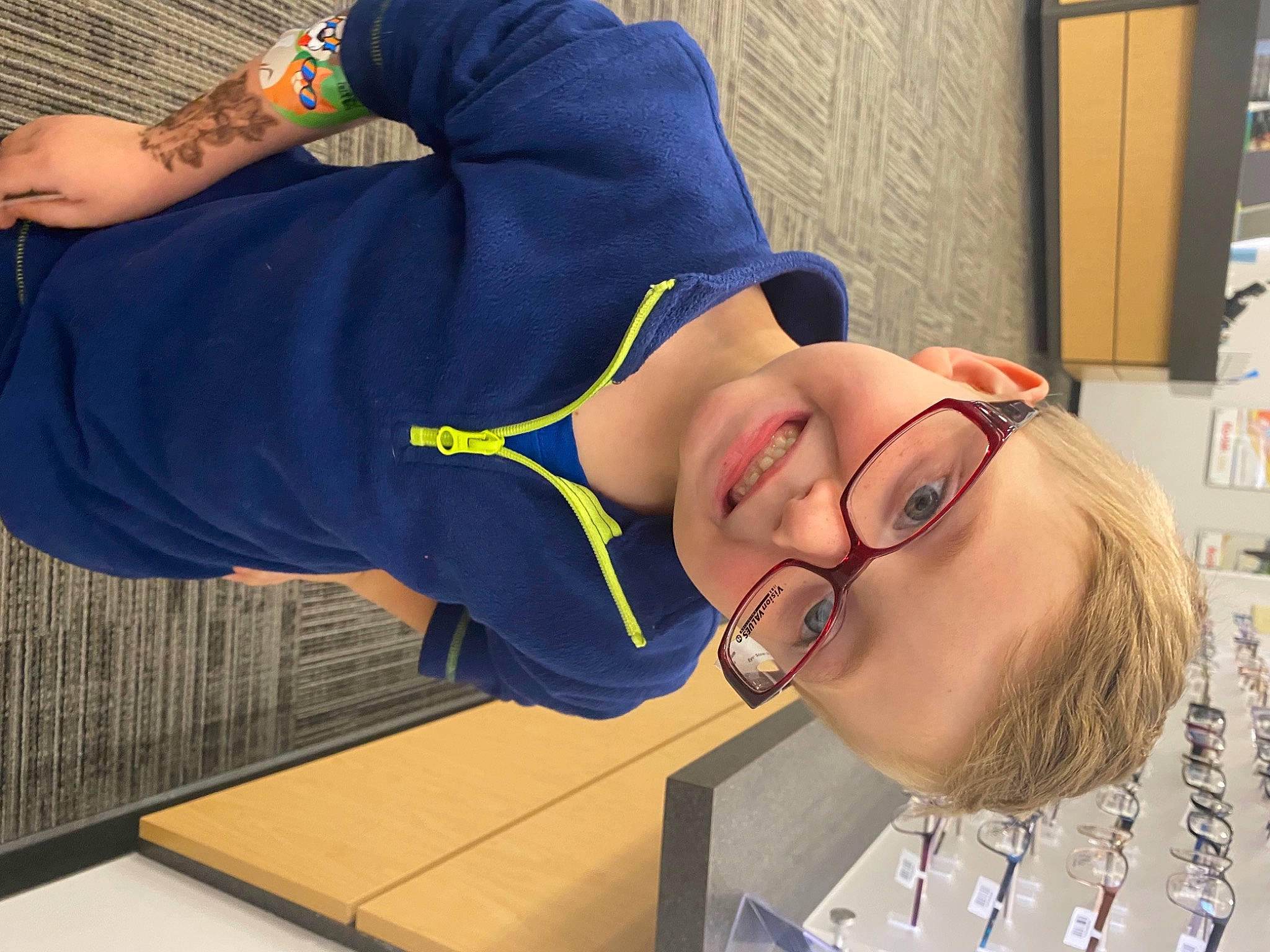 Jaxxson is registered to the contest to win money with this photo: child, elbow, eyewear, fun, glasses, happy, hat, human_leg, joy, knee, leisure, mouth, person, room, shelf, smile, sportswear, thigh, vision_care, wrist