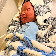 Tyreek is registered to the contest to win money with this photo: newborn, baby, blanket, hospital, bassinet, smile, sleeping, cute, infant, clothing, hooded_blanket, face, portrait, cozy, soft_texture, child, newborn_baby, wrapped, happy, baby_boy