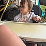 toddler, child, high_chair, outdoor, porch, curious, baby, face, person, clothing, foot, table, plastic, furniture, window, grass, house, daylight, sleeve, expression