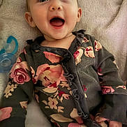 Lucifia is registered to the contest to win money with this photo: baby, child, infant, smiling, happy, face, eyes, mouth, clothing, floral_pattern, blanket, pacifier, hand, lying_down, cozy, cute, portrait, indoors, soft, comfort
