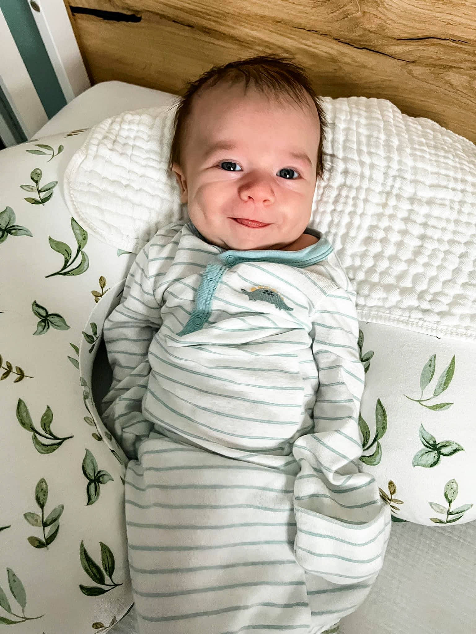 Hayes is registered to the contest to win money with this photo: baby, baby_products, baby_toddler_clothing, bedding, child, comfort, facial_expression, happy, linens, outerwear, pattern, person, product, room, sitting, skin, sleeve, smile, t_shirt, textile