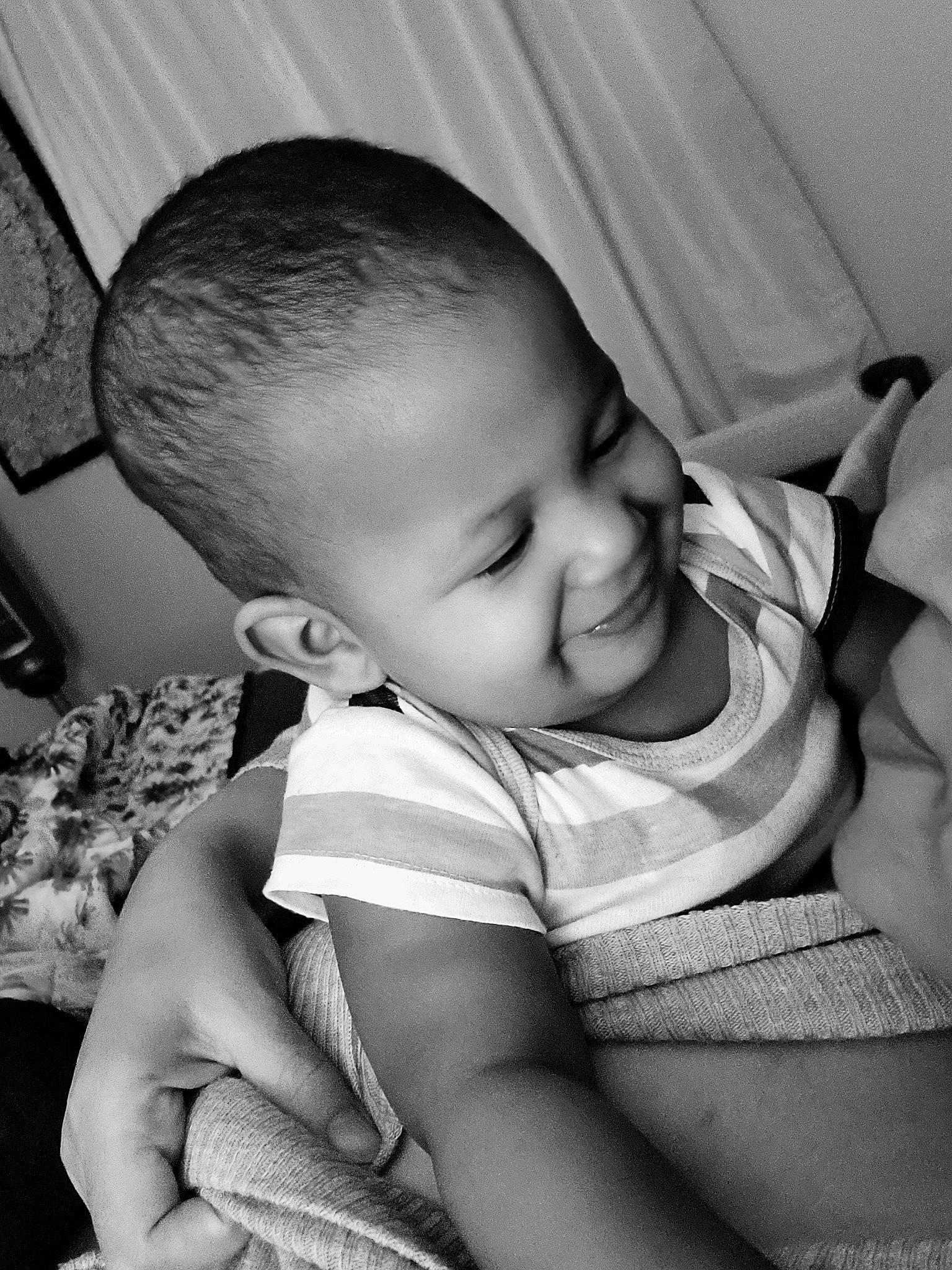 Azaiah is registered to the contest to win money with this photo: arm, baby, baby_toddler_clothing, black, black_and_white, cheek, chin, comfort, eyebrow, flash_photography, hairstyle, happy, iris, joy, mouth, nose, person, photograph, skin, smile