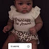 baby, infant, child, sitting, clothing, white_shirt, leopard_print, text_overlay, countdown_timer, portrait, cute, face, legs, dark_background, soft_focus, young_child, person, expression, casual, indoors
