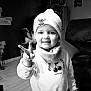 Louise participe au concours pour gagner de l'argent avec cette photo : child, toddler, smiling, peace_sign, hat, knit_hat, scarf, sweater, indoor, black_and_white, face, person, cute, happy, portrait, young_child, living_room, furniture, floor, cozy