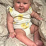 baby, infant, smiling, tongue_out, onesie, yellow_flower, blanket, soft_texture, cute, chubby, skin, hand, foot, seated, indoors, cozy, happy, portrait, child, person