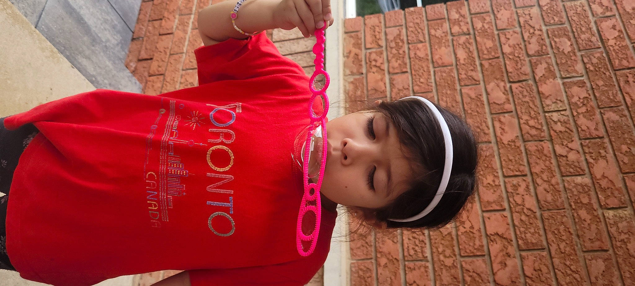 Danna is registered to the contest to win money with this photo: carmine, cylinder, eyewear, happy, magenta, mammal, person, red, sleeve, t_shirt, textile, wood