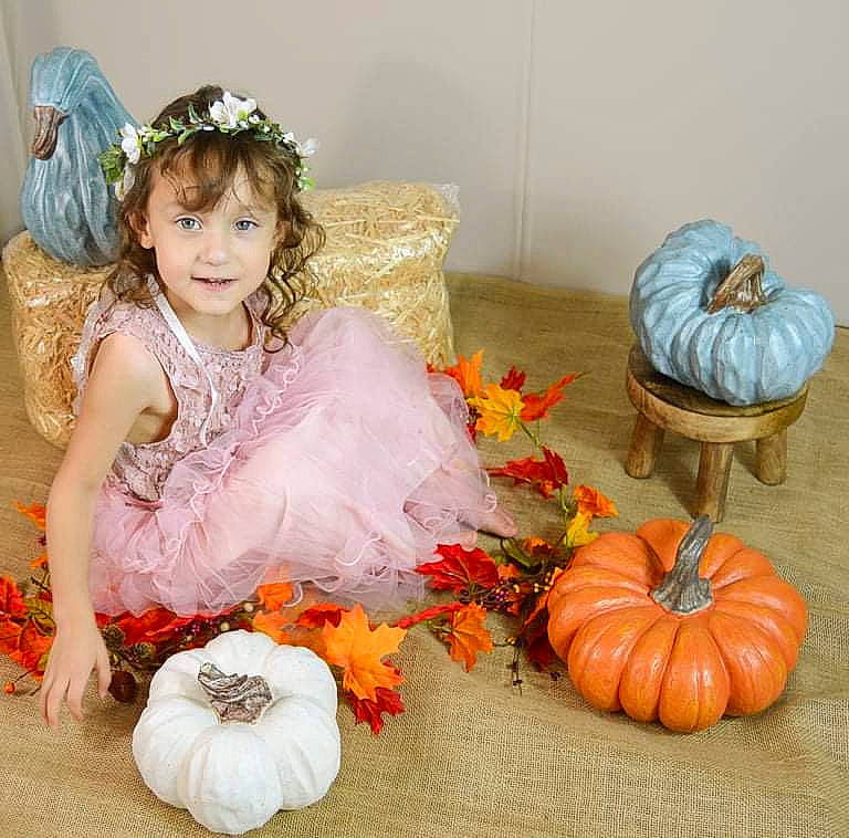 Vannessa joined the competition — help win amazing prizes! baby_toddler_clothing, calabaza, child, couch, cucurbita, dress, embellishment, gourd, happy, headpiece, natural_foods, orange, person, petal, plant, pumpkin, squash, textile, toddler, vegetable