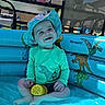 Zayden is registered to the contest to win money with this photo: toddler, child, swimwear, hat, inflatable_pool, dinosaur, toy, outdoor, summer, water, smiling, blue, green, sitting, playful, sunlight, backyard, happy, casual, cute