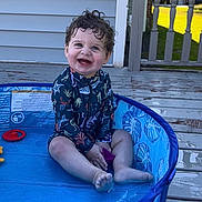 Zayden joined the competition — help win amazing prizes! toddler, child, pool, water, outdoor, smile, curly_hair, blue_eyes, play, deck, sunlight, clothing, toy, happy, sitting, skin, feet, person, summer, blue