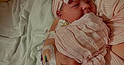 Raylynn is registered to the contest to win money with this photo: newborn, baby, infant, swaddled, pink_blanket, headband, hospital, iv_line, hand, person, bed, white_sheet, soft_fabric, closeup, portrait, resting, hospital_room, care, tender, wrapped