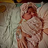 newborn, baby, infant, swaddled, pink_blanket, headband, hospital, iv_line, hand, person, bed, white_sheet, soft_fabric, closeup, portrait, resting, hospital_room, care, tender, wrapped