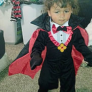 Tarious joined the competition — help win amazing prizes! child, costume, vampire, cape, indoor, carpet, laundry, clothes, person, portrait, cute, toddler, black_clothing, red_clothing, fun, holiday, party, dress_up, young_child, curly_hair