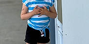 Paisley joined the competition — help win amazing prizes! child, smiling, braided_hair, blue_and_white_striped_shirt, black_shorts, pink_crocs, outdoor, concrete, bandage, temporary_tattoos, happy, standing, person, casual_clothing, daylight, trash_bin, metallic_structure, playful, young, kid