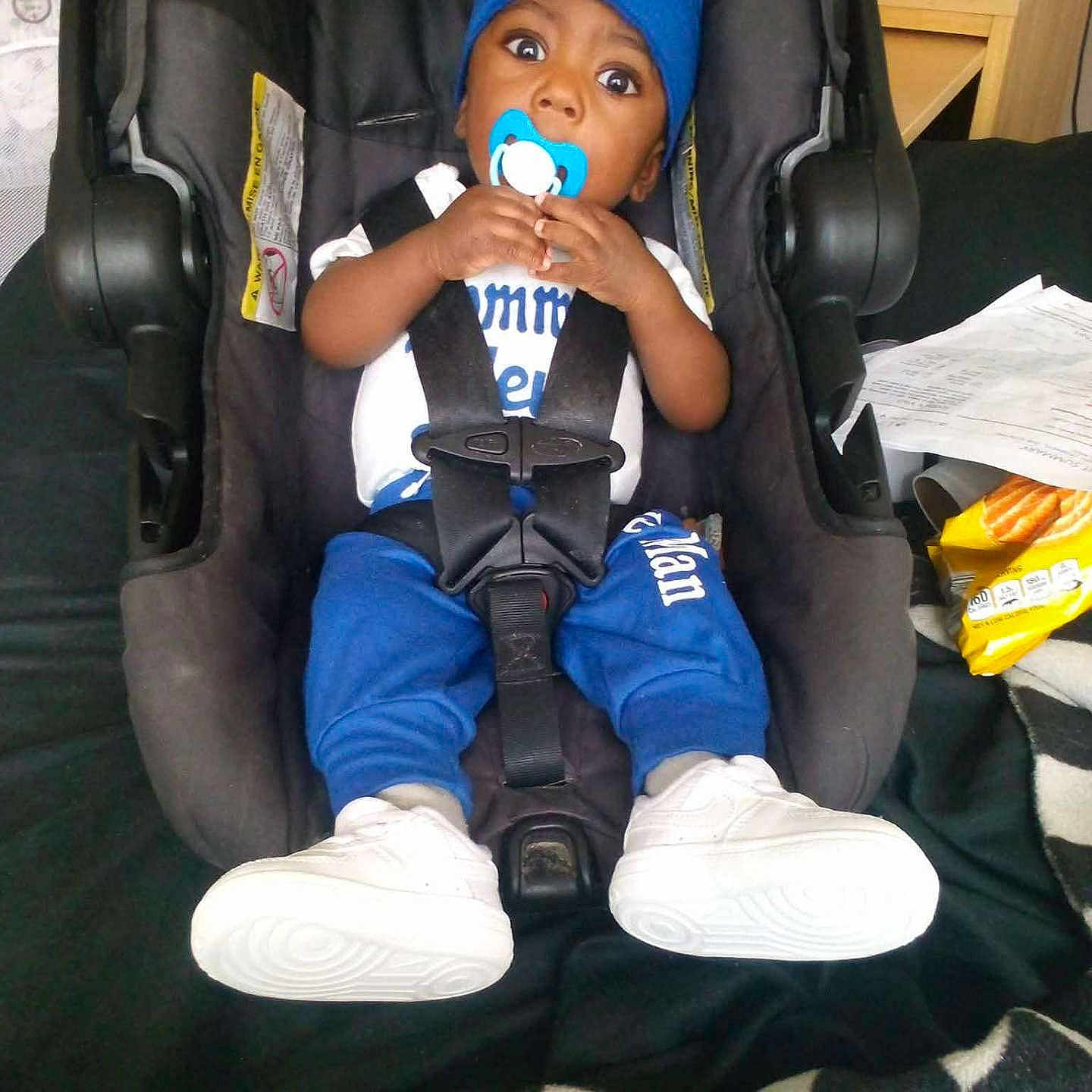 Damarion Gooden is registered to the contest to win money with this photo: child, toddler, baby, boy, car_seat, pacifier, blue_hat, blue_clothing, white_shoes, sneakers, sitting, strapped_in, wide_eyes, portrait, indoor, vehicle, car_interior, seat_belt, household_items, checkered_blanket
