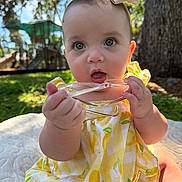 Selena joined the competition — help win amazing prizes! baby, child, infant, outdoor, yellow_dress, bow, blue_eyes, grass, tree, sunlight, face, hand, playing, summer, nature, cute, portrait, sitting, blanket, park