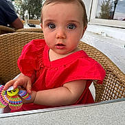 Garance a rejoint le concours — aidez-le/la à gagner de superbes lots ! baby, child, red_dress, wicker_chair, toy, pinwheel, curious, outdoor, cafe, table, person, portrait, cute, innocent, seated, face, expression, colorful, hands, young